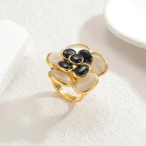 Detail of camellia ring featuring black petals, white cat eye stones, and gold finish