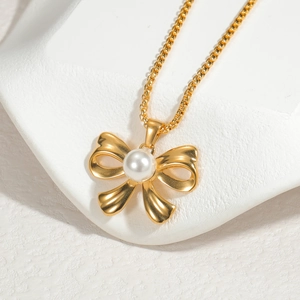 Elegant gold bow necklace with white pearl pendant on minimalist geometric display