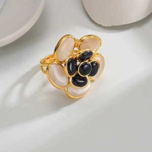 Macro detail of golden camellia ring with white opal petals and black bead flower core