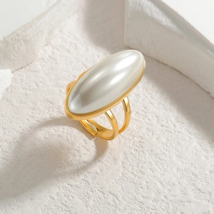 Detailed view of an oval pearl set in a gold plated open ring on white stone