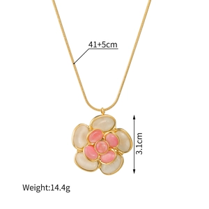 Collana con ciondolo a camelia dorata con pietre bianche e rosa su sfondo bianco