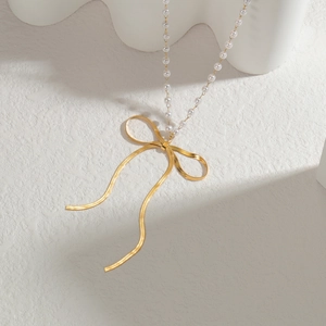 Elegante Halskette mit goldener Schleife, weißen Perlen und hängenden Metallquasten