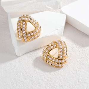 Elegant gold triangle earrings with pearls and rope texture on white stone blocks