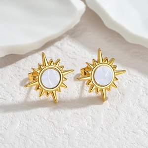Boucles d'oreilles fleur de soleil dorées avec nacre blanche sur fond de pierre