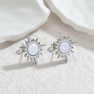 Boucles d'oreilles soleil en acier inoxydable avec pierre bleu clair sur support blanc