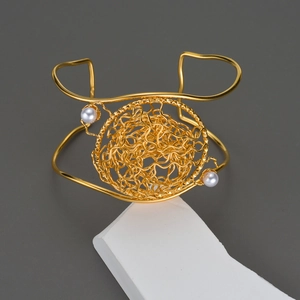 Bracciale rigido dorato con nido di fili metallici artistici e dettagli in perle
