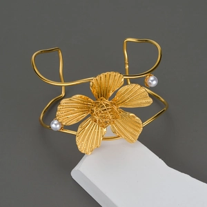 Dettaglio macro del bracciale a fiore dorato con petali testurizzati e perle eleganti