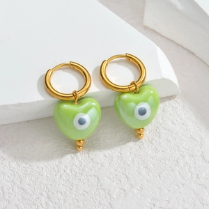 Boucles d'oreilles cœur œil maléfique dorées sur un support en pierre minimaliste