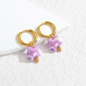 Détail de boucles d'oreilles étoiles en céramique avec pois blancs sur créoles dorées 18K