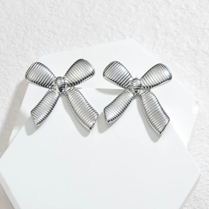 Boucles d'oreilles nœud en argent avec texture rayée sur un présentoir blanc élégant