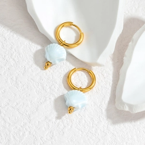 Detail von 18K Gold Muschelohrringen mit hellblauen Anhängern auf weißem Hintergrund