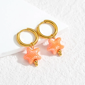 Détail macro de créoles en or 18 carats avec pendentifs étoile de mer orange texturés
