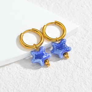 Détail de boucles d'oreilles étoile de mer dorées avec texture céramique bleue