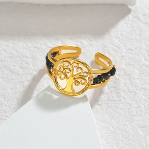 Bague arbre de vie dorée ajustable avec perles noires sur un socle en pierre minimaliste