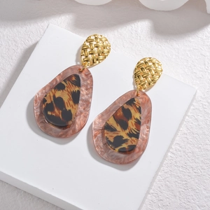 Boucles d'oreilles rétro en acétate léopard avec clous tressés dorés sur un socle