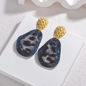 Boucles d'oreilles en acétate léopard avec clous en métal doré sur présentoir en pierre