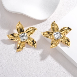 Elegant gold flower earrings with zircon center on minimalist white background