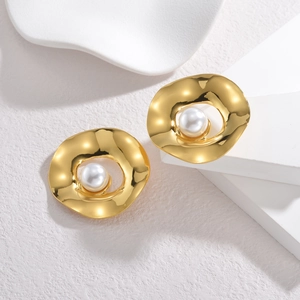 Orecchini vintage in oro a disco irregolare con perla bianca su superficie di pietra