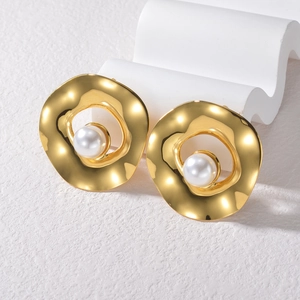 Orecchini a cerchio dorati ondulati con perla bianca su sfondo bianco minimalista puro