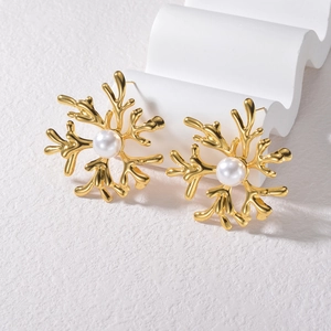 Minimalist gold irregular snowflake stud earrings with white pearls on a white prop