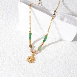 Bohemian gold sun pendant necklace with colorful beads on textured white stone