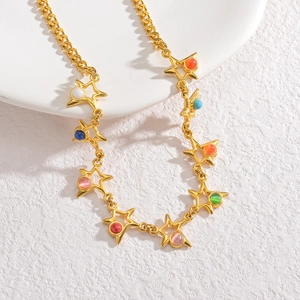 Détail d'un collier chaîne gourmette dorée avec pendentifs étoiles colorés sur socle