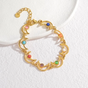 Détail du bracelet doré en forme de lune avec perles colorées sur plateau blanc