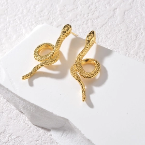 Vintage golden snake stud earrings with textured scales on a minimalist white pedestal