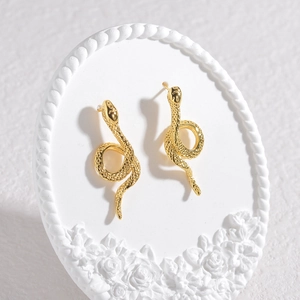Vintage gold snake stud earrings with textured scales on an elegant white pedestal
