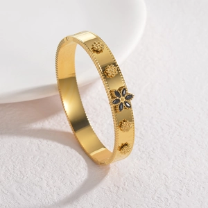 Elegant gold-plated stainless steel flower bangle with black gemstone on white base