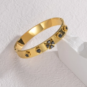 Gold-plated stainless steel bangle with black geometric inlays and beaded edges