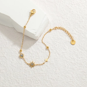 Elegant gold stainless steel star bracelet with sparkling crystals on white stone