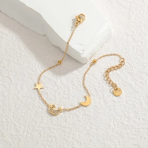Elegant gold stainless steel star and moon charm bracelet displayed on a white stone