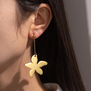 Vintage gold-tone titanium steel flower drop earrings worn by a model in soft light