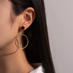 Minimalist geometric hoop earrings with black studs and gold rings on female model