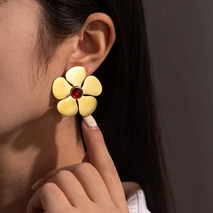 Boucles d'oreilles fleur vintage dorées 18K avec pierre rouge sur modèle