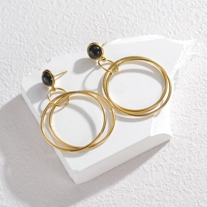 Elegant gold multi-layer circular earrings with black onyx studs on a white stone base