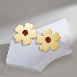 Exaggerated matte gold flower earrings with red ruby stone centers on stone base