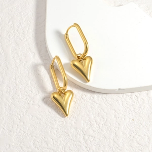 Polished 18K gold-plated heart drop earrings with oval hooks on minimalist background
