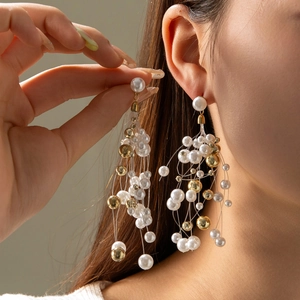 Élégantes boucles d'oreilles longues à pompons en perles et perles dorées portées