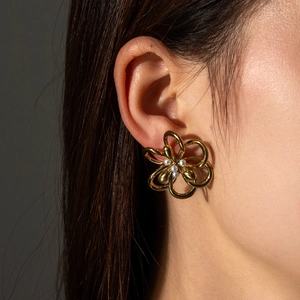Élégantes boucles d'oreilles fleurs évidées dorées avec perles sur l'oreille d'un mannequin