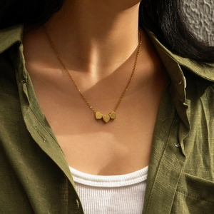 Collier doré minimaliste avec trois pendentifs en cœur porté au cou, vue lifestyle