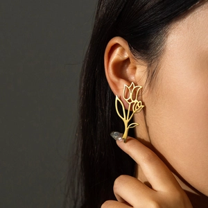 Eleganti orecchini a tulipano dorati indossati da una modella su sfondo scuro minimale