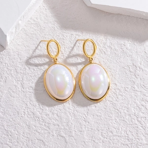 Eleganti orecchini placcati oro con conchiglia di perla ovale su sfondo di pietra