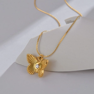 Elegante collana a farfalla dorata con ciondolo in zircone bianco su sfondo bianco