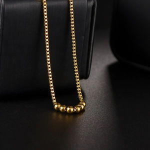 Collier minimaliste à chaîne box dorée avec six pendentifs sphériques polis et brillants