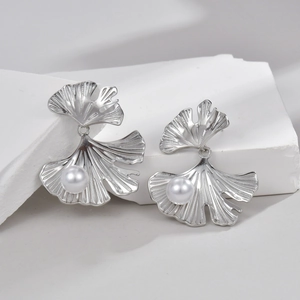 Silver ginkgo leaf earrings with pearls and zircon on a minimalist white stone base