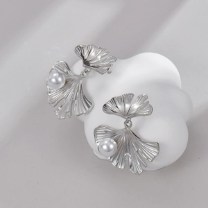 Detail of silver ginkgo leaf earrings with pearls on a minimalist white display