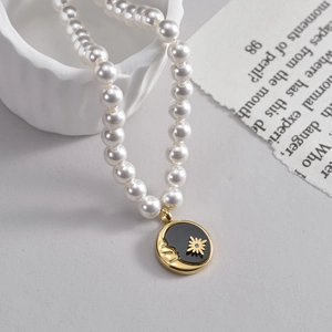 Elegant pearl necklace with a black celestial medallion featuring gold moon and star