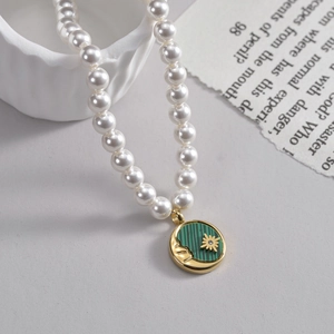 Stainless steel pearl necklace featuring a gold moon and star coin pendant with green inlay